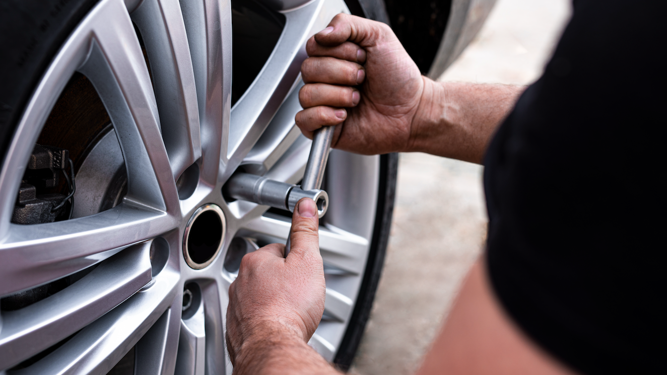People shaking hands next to a car