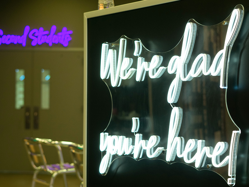 An led sign that says we're glad you're here!